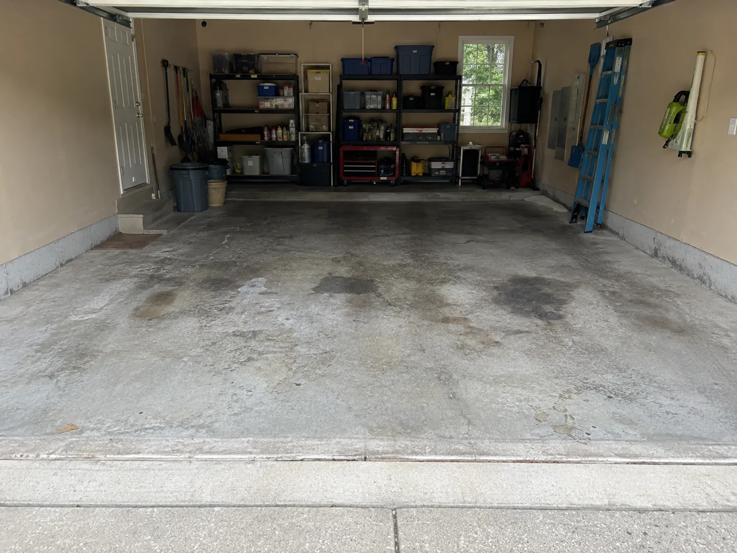 Two-car garage with a worn, stained bare concrete floor before coating