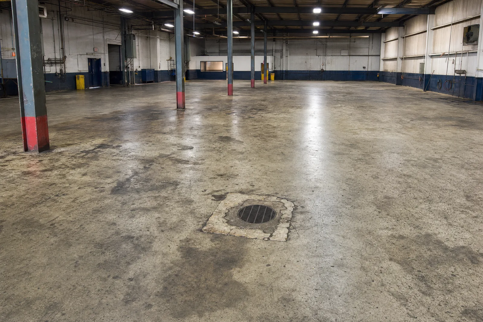 Commercial shop floor of bare concrete heavily stained with oil and grease