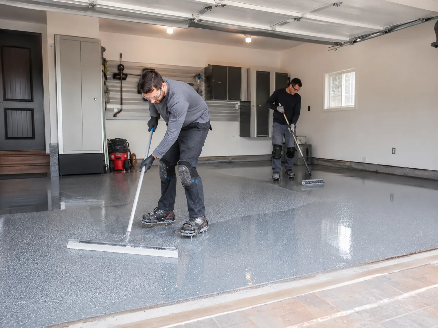 Two installers applying base coat with squeegee and roller