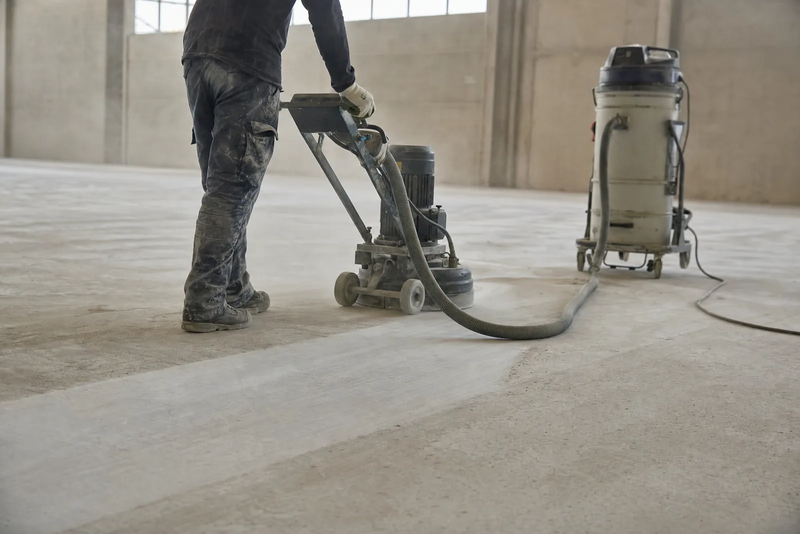 Operator running a walk-behind diamond grinder with dust extraction