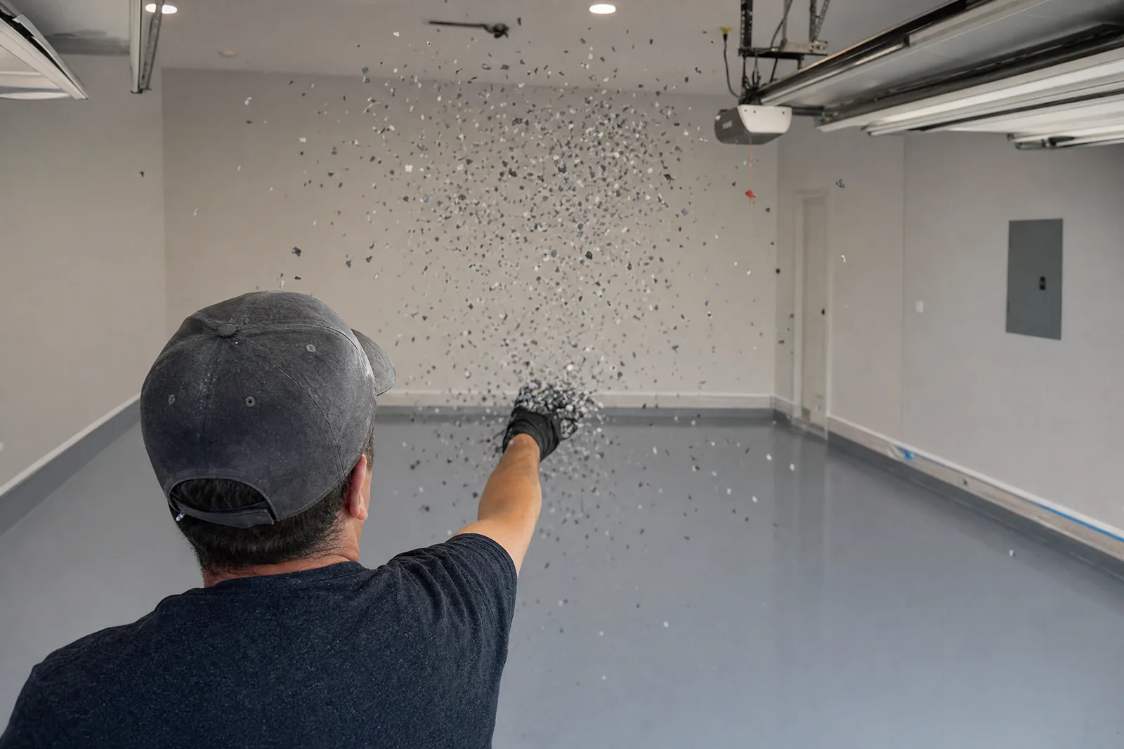 Installer broadcasting vinyl flake chips over a wet epoxy base coat