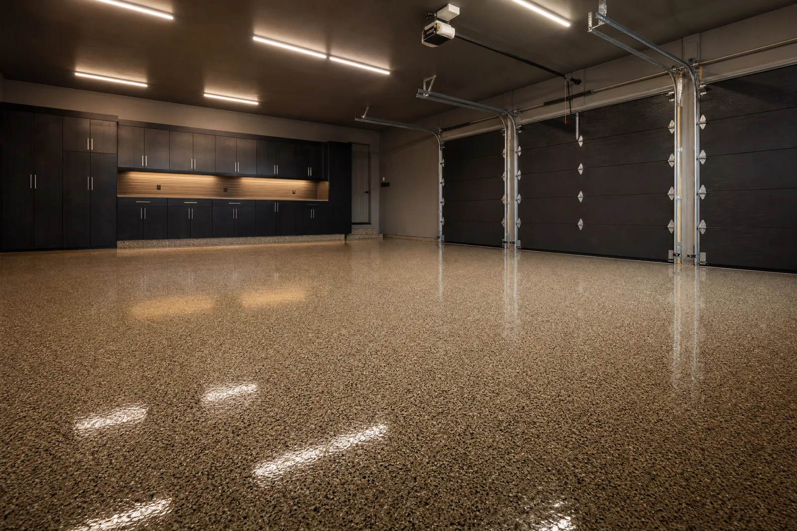 Spacious three-car residential garage with tan and brown flake epoxy floor